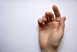 Photo of a hand having a wound covered by plaster on a finger on white background